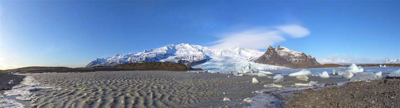 Gletschersee im Sonnenlicht mit Bergen und Gletscherzunge