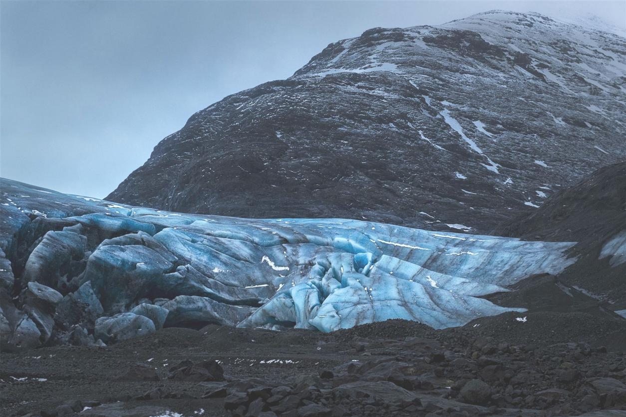 Blick auf leuchtend blauen Gletscher mit Berg im Hintergrund in Island