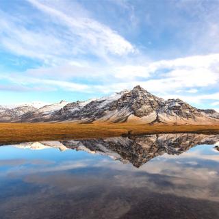Hinter weiter ebene schneebedeckte Berge die sich im klaren Wasser spiegeln